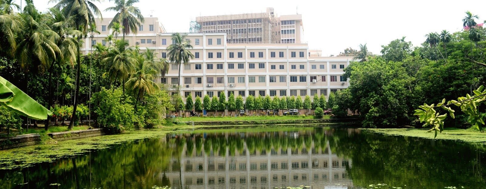 Indian Statistical Institute, Kolkata campus building beside a lake, framed by palm and mango trees